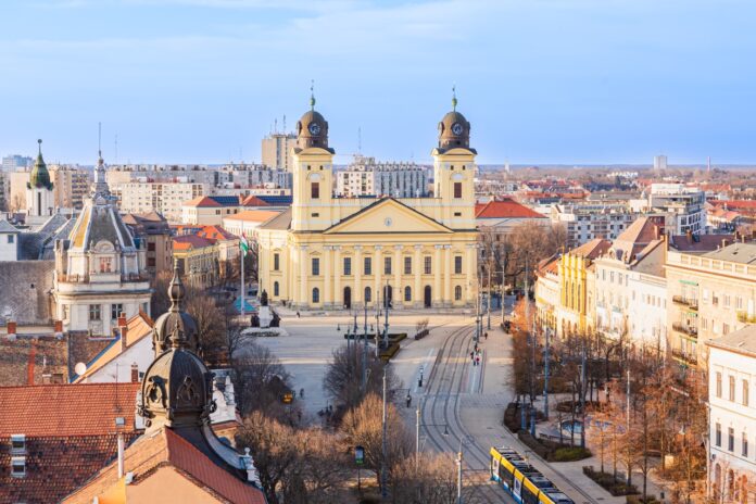 Debrecen városképe modern irodaházakkal, fejlesztésekkel és új beruházásokkal, amelyek a város gazdasági fejlődését jelképezik.