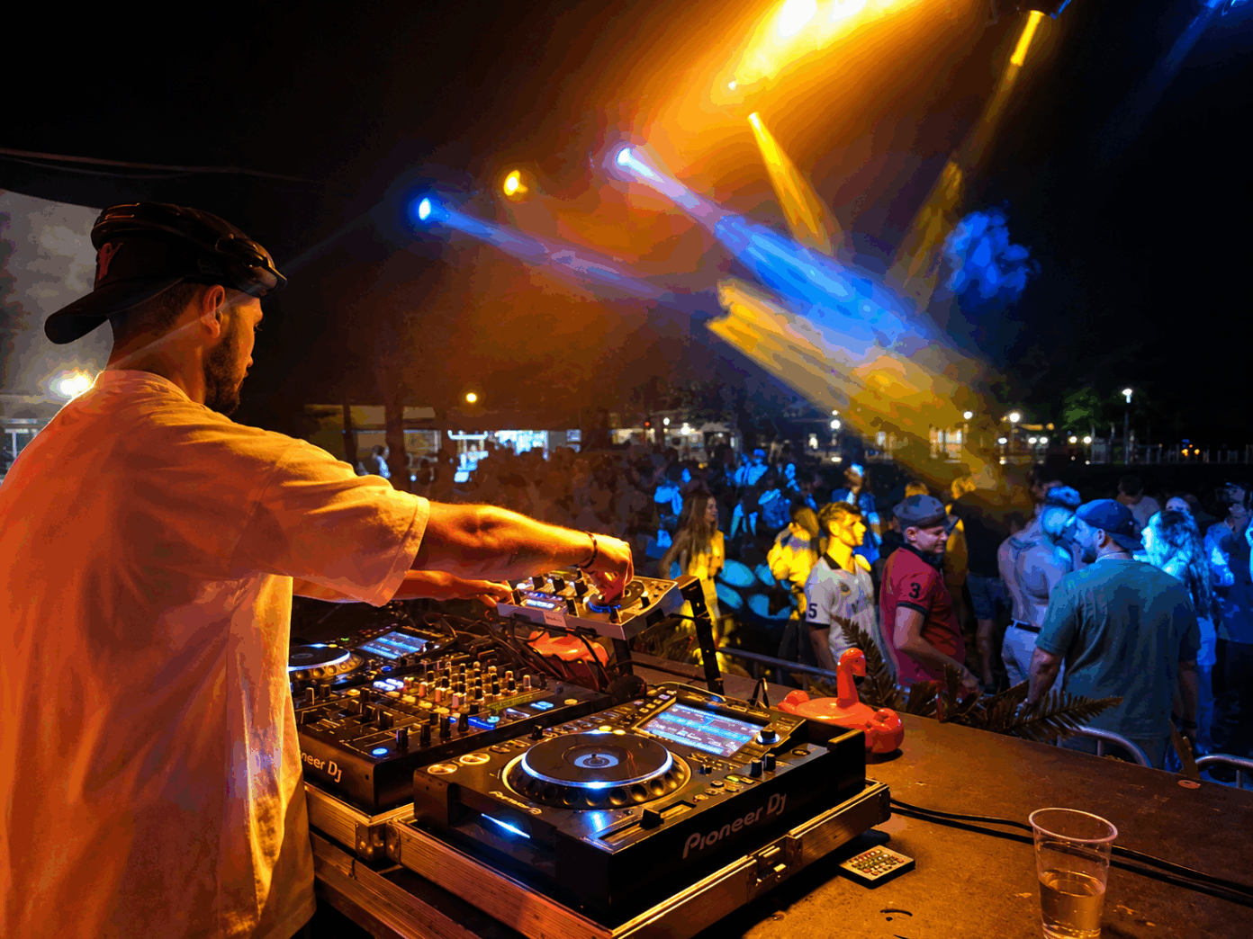 c DJ játszik a Sunset Serenade rendezvényen a Kiskőrösi Rónaszéki Fürdő szabadtéri színpadán, a háttérben a közönség és a naplementés esti hangulat.